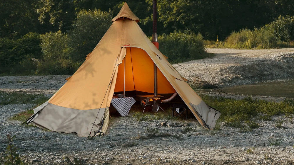 Kachels, tipitent met open deur en warm licht binnen op een kiezelvlakte bij het water