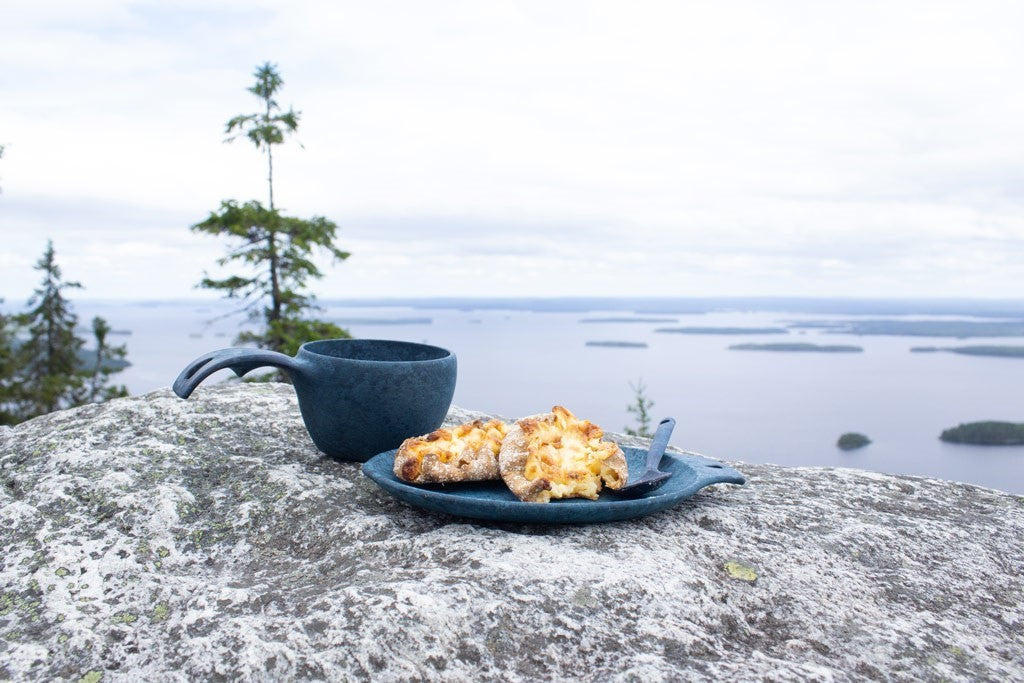 Kupilka 14 Petite Assiette bleue avec des amuse-bouches sur un rocher au-dessus d'un lac, près d'une tasse bleue