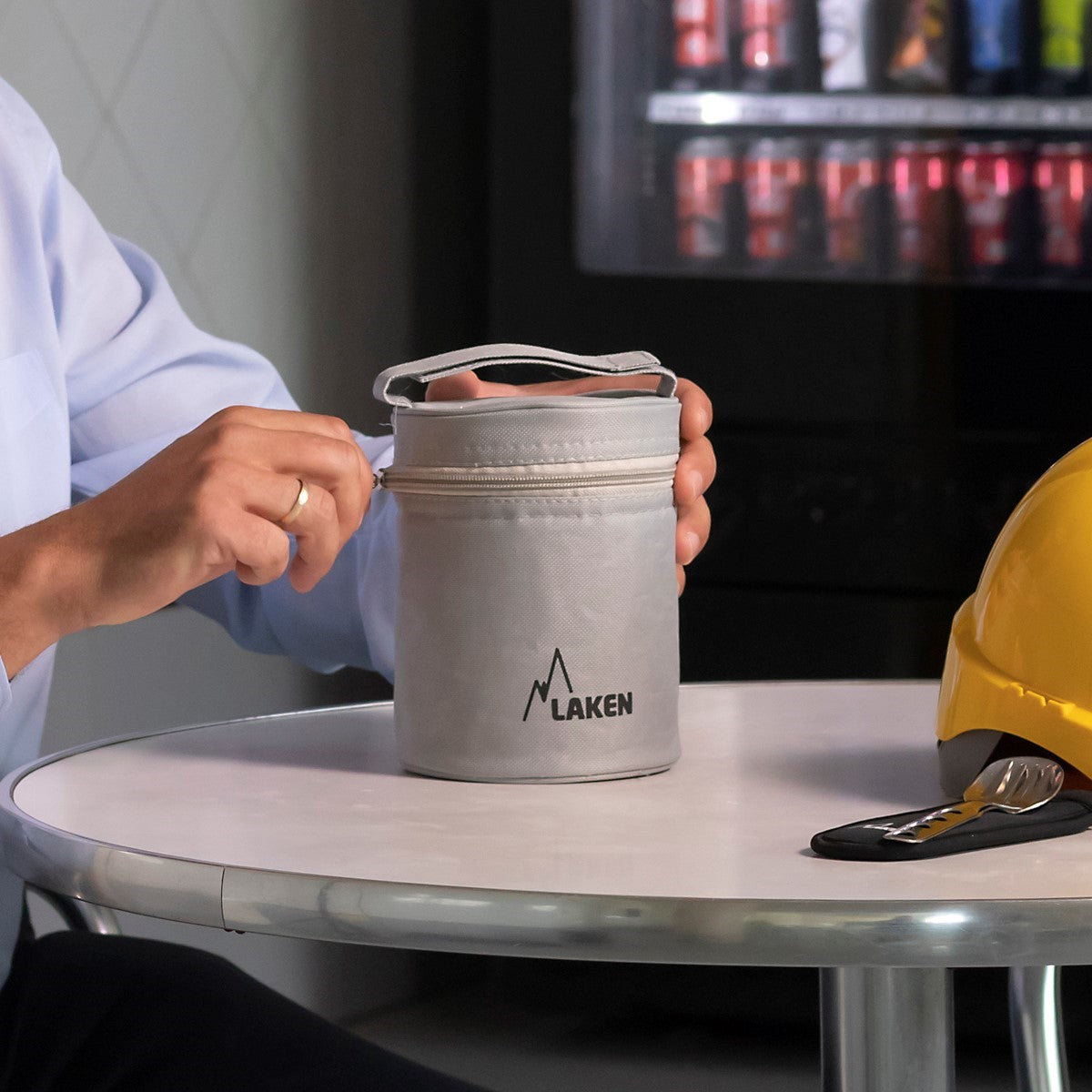 Lunchbox isotherme Laken dans le sac de transport gris sur une table, à côté d'un casque de chantier jaune