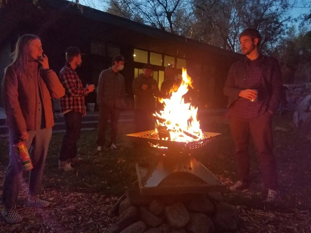 Foyer extérieur Winnerwell Flat avec un feu le soir au milieu d'un petit groupe de personnes