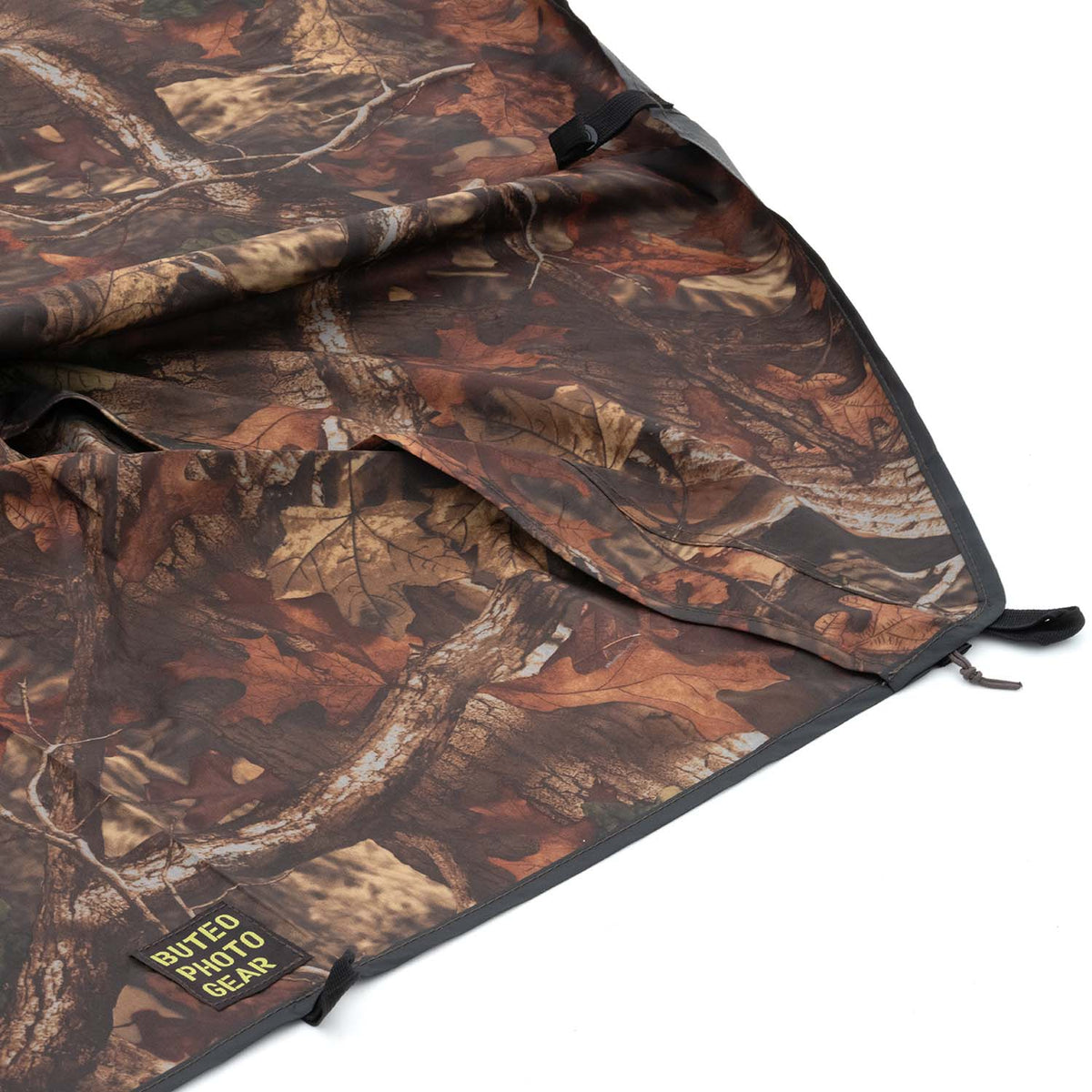 Housse de pluie Buteo Falco Mark IV en camouflage feuillage brun, détail du coin avec boucle et étiquette logo