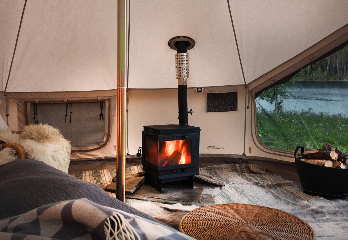 CanvasCamp Bison allumé dans une tente en toile aménagée avec peaux, coussins et panier en osier
