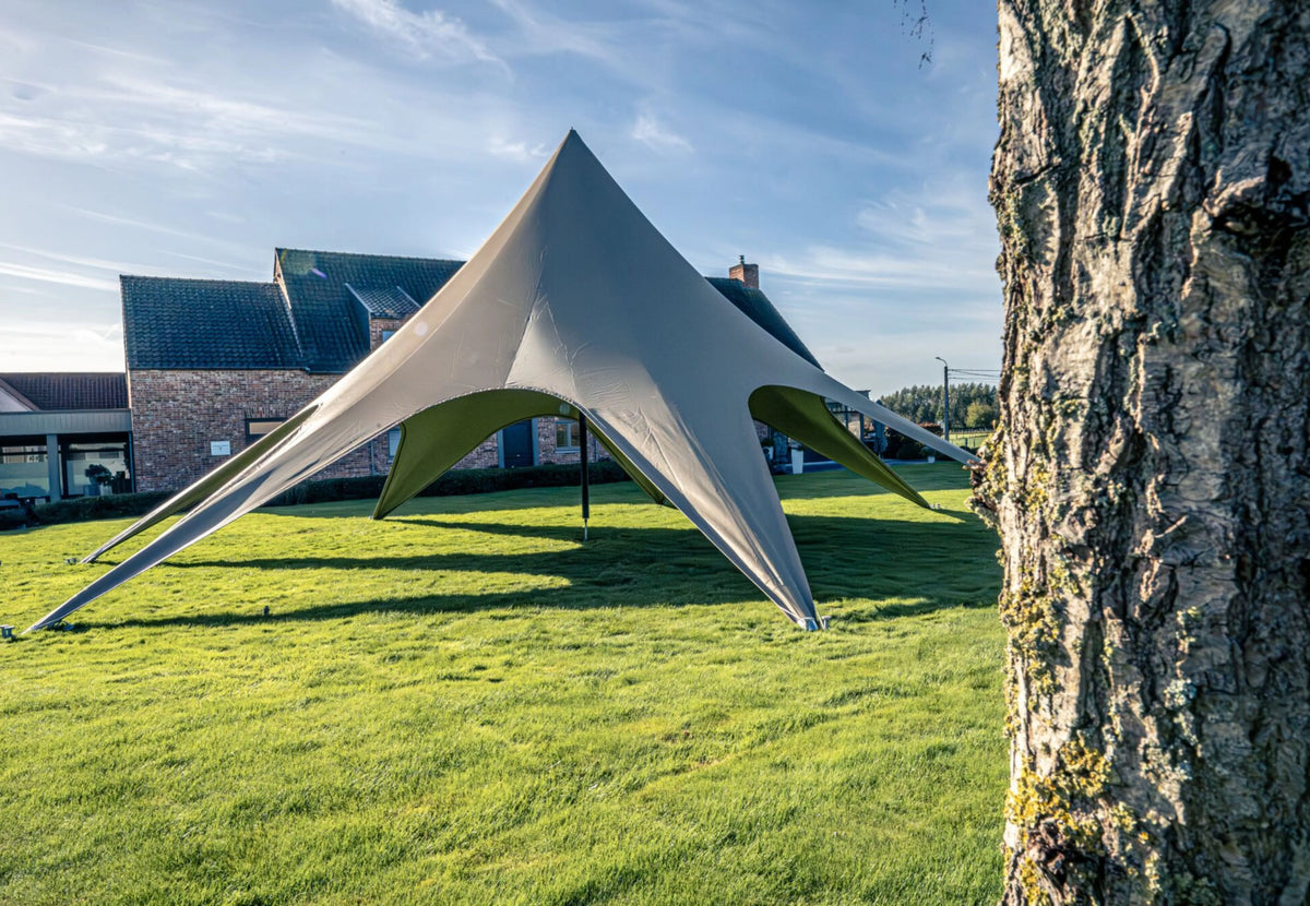 Tente événementielle CanvasCamp StarShade Pro grise sur une pelouse devant une maison, vue près d'un arbre