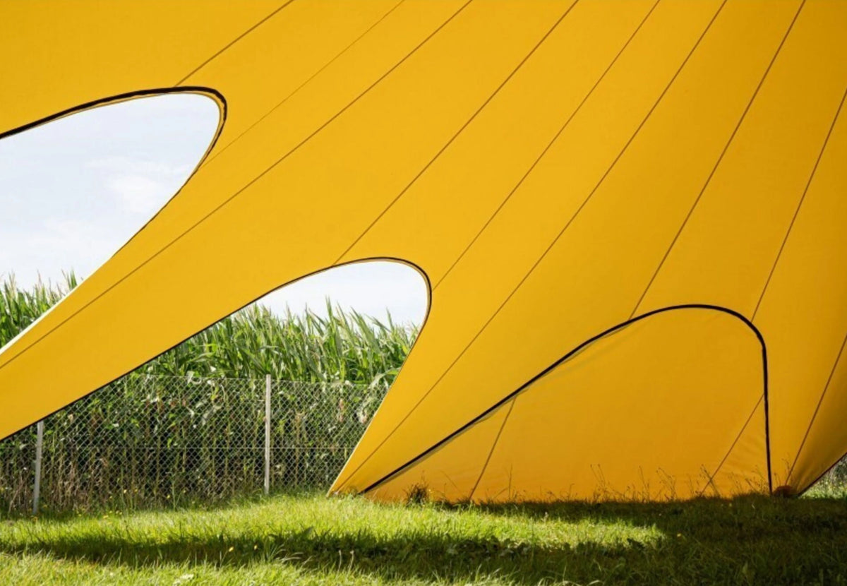 Paroi latérale fermée CanvasCamp StarShade Pro jaune avec ouvertures arrondies et vue sur le maïs