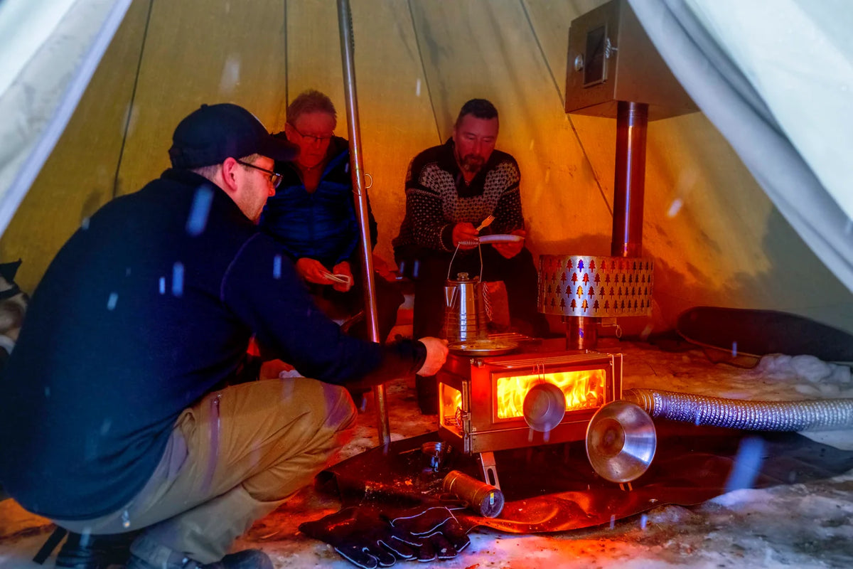 Winnerwell Nomad Plus Double View allumé dans une tente en toile avec trois personnes autour