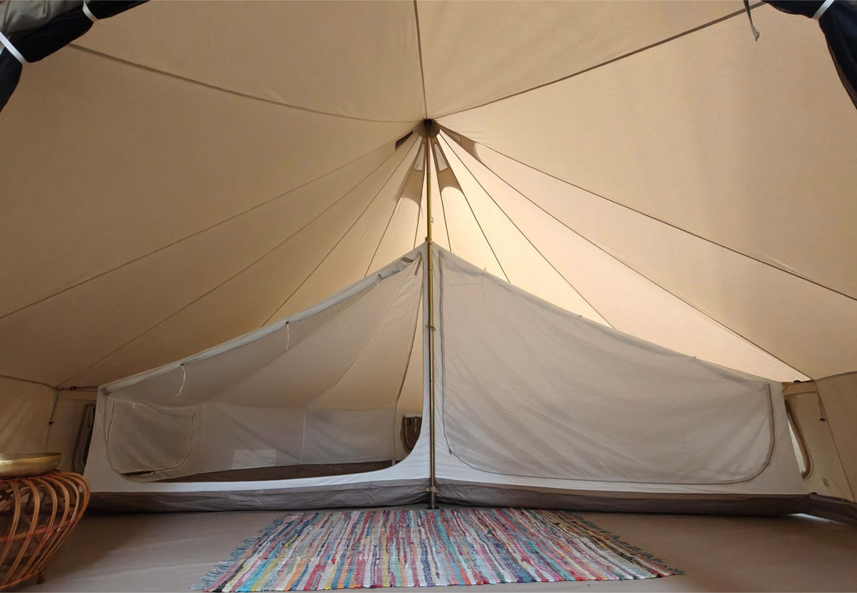 Tente intérieure CanvasCamp Sibley suspendue dans une tente cloche, vue de face avec un tapis coloré