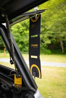 WakaWaka Solar 20 suspendu au hayon ouvert d'une voiture, avec une batterie externe jaune en dessous