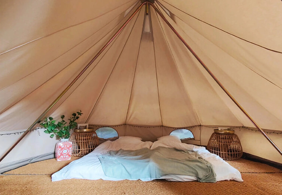 DuoPod CanvasCamp dans une tente cloche Sibley vue de l'intérieur, avec un lit double au centre