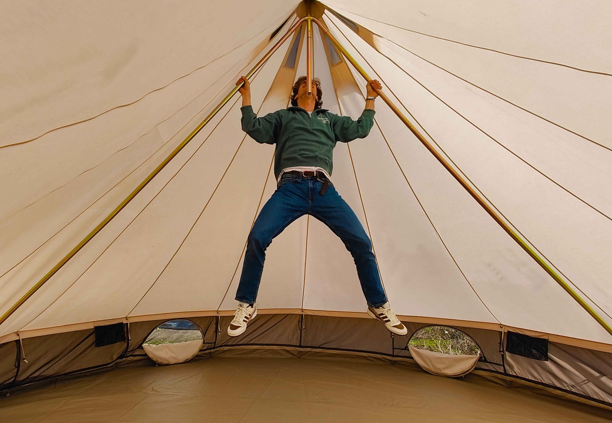 DuoPod CanvasCamp dans une tente cloche, un homme suspendu aux deux mâts inclinés