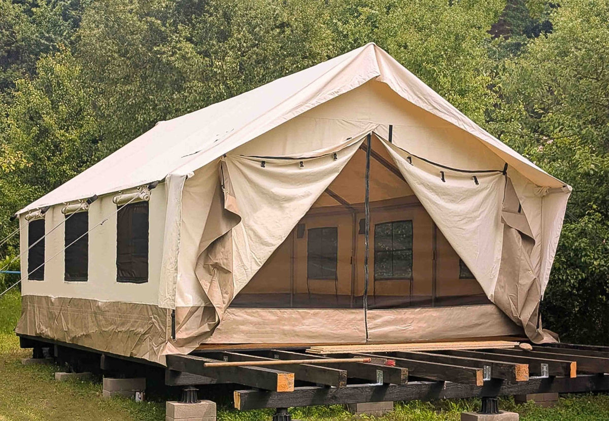 CanvasCamp Heavy Duty Safari Tent sur une plateforme en bois entre les arbres, porte ouverte