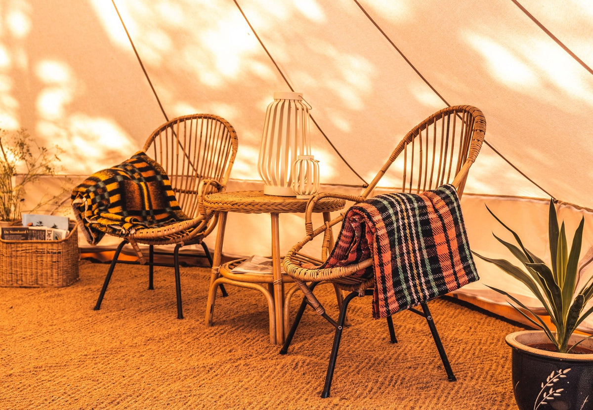Tapis coco demi-rond CanvasCamp sous deux chaises en osier et une petite table dans une tente