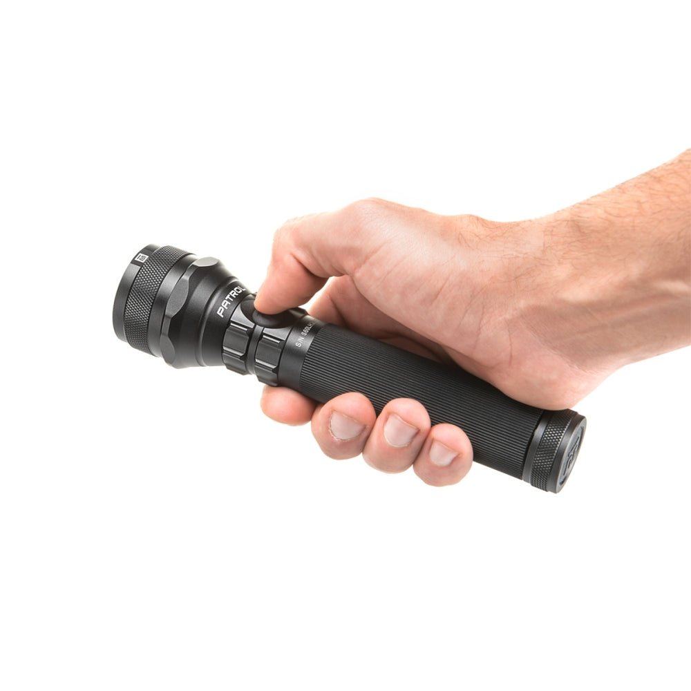 Lampe torche Mactronic Patrol en main, le pouce près du bouton sur la tête