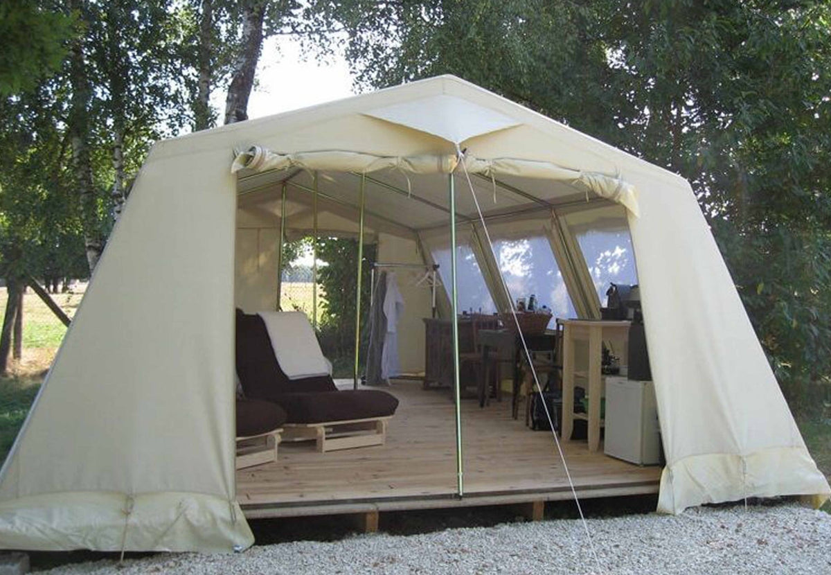 Tente de patrouille CanvasCamp Mess Traveller aménagée avec un fauteuil lounge sur une plateforme en bois