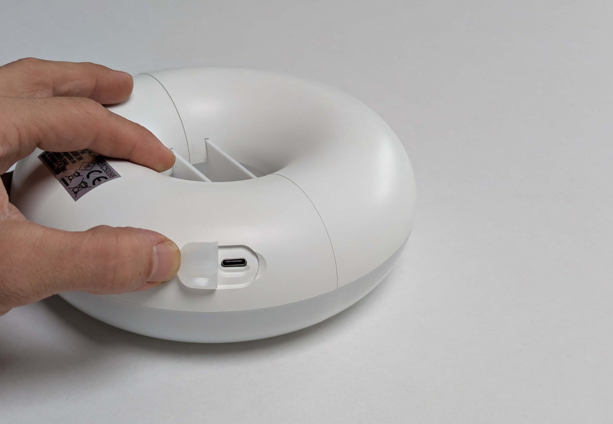 Éclairage de tente rechargeable CanvasCamp, main ouvrant le cache du port de charge