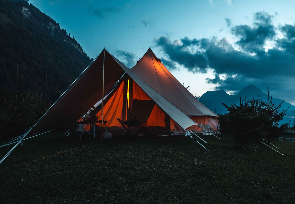 CanvasCamp Sibley Belltent Connector entre deux tentes cloches éclairées le soir près des montagnes