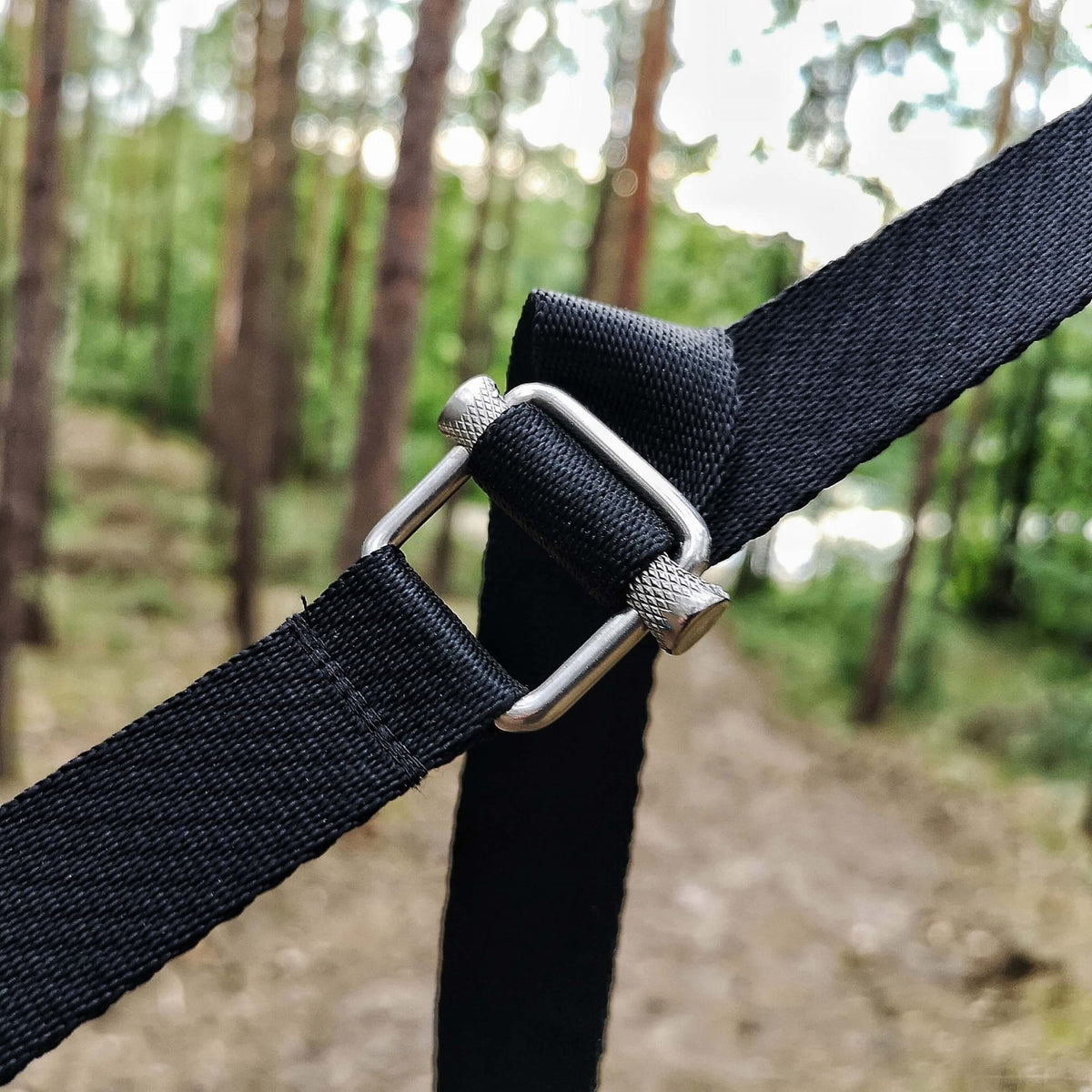 Triplander Quick Drag, boucle métallique et sangle noire en gros plan dans une forêt