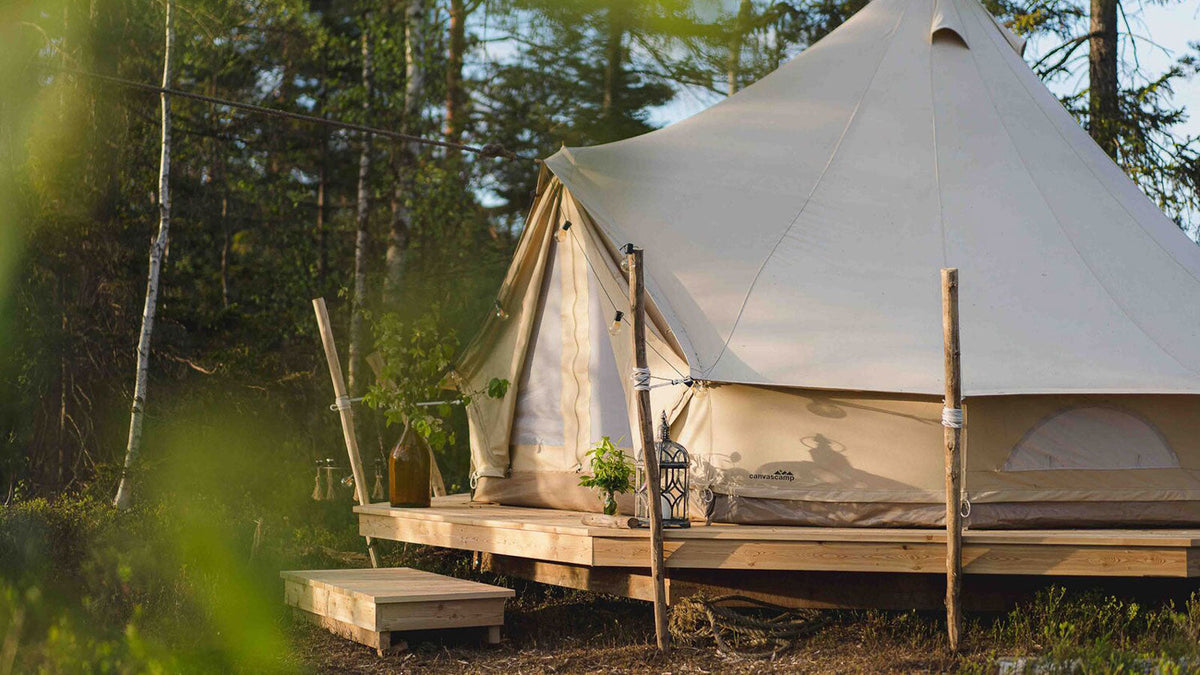 ProTech tenten, witte bell tent op een houten vlonder aan de bosrand in de zon
