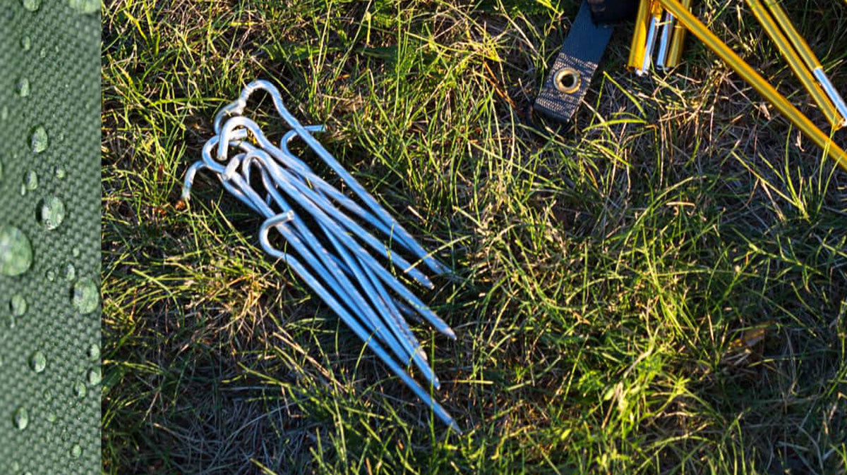 Tentharingen, bundel zilverkleurige haringen met haak in het gras naast een gele tentstok