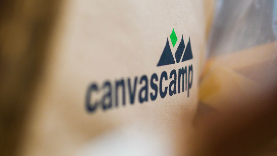 CanvasCamp logo met bergen en een groene ruit op beige tentdoek, van dichtbij