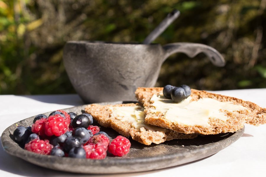 Kupilka 44 assiette noire avec crackers et fruits rouges, une tasse noire en arrière-plan