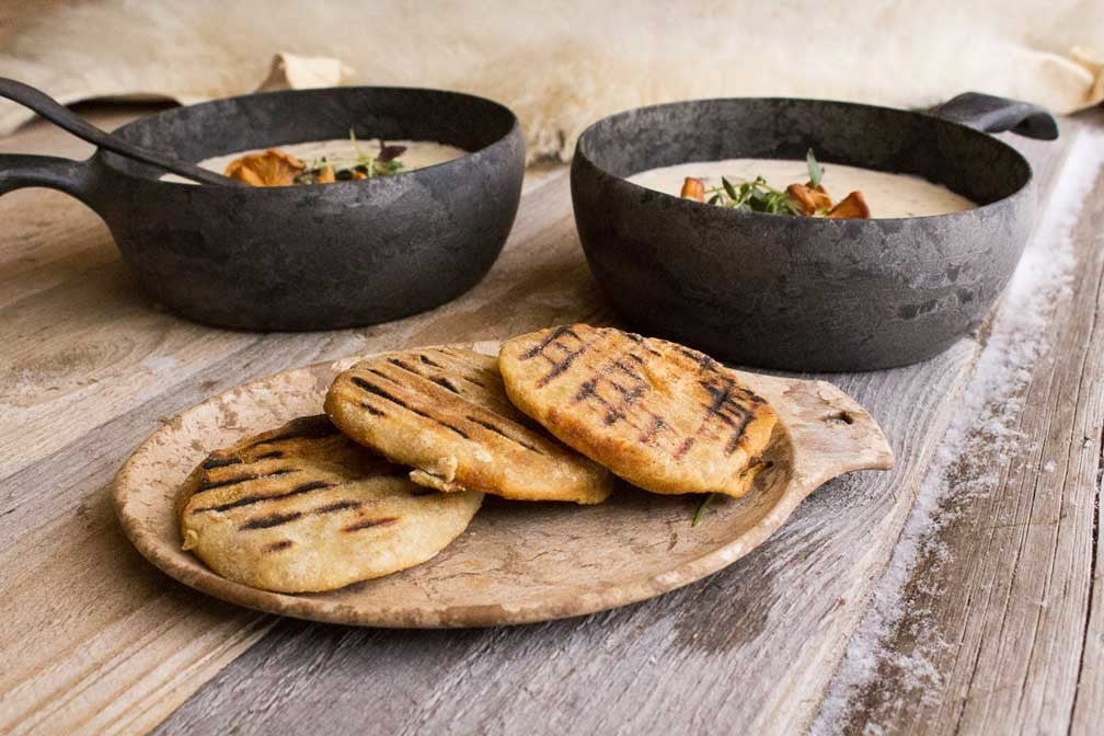 Kupilka 14 Petite Assiette en brun avec pains grillés sur une table en bois à côté de casseroles de soupe