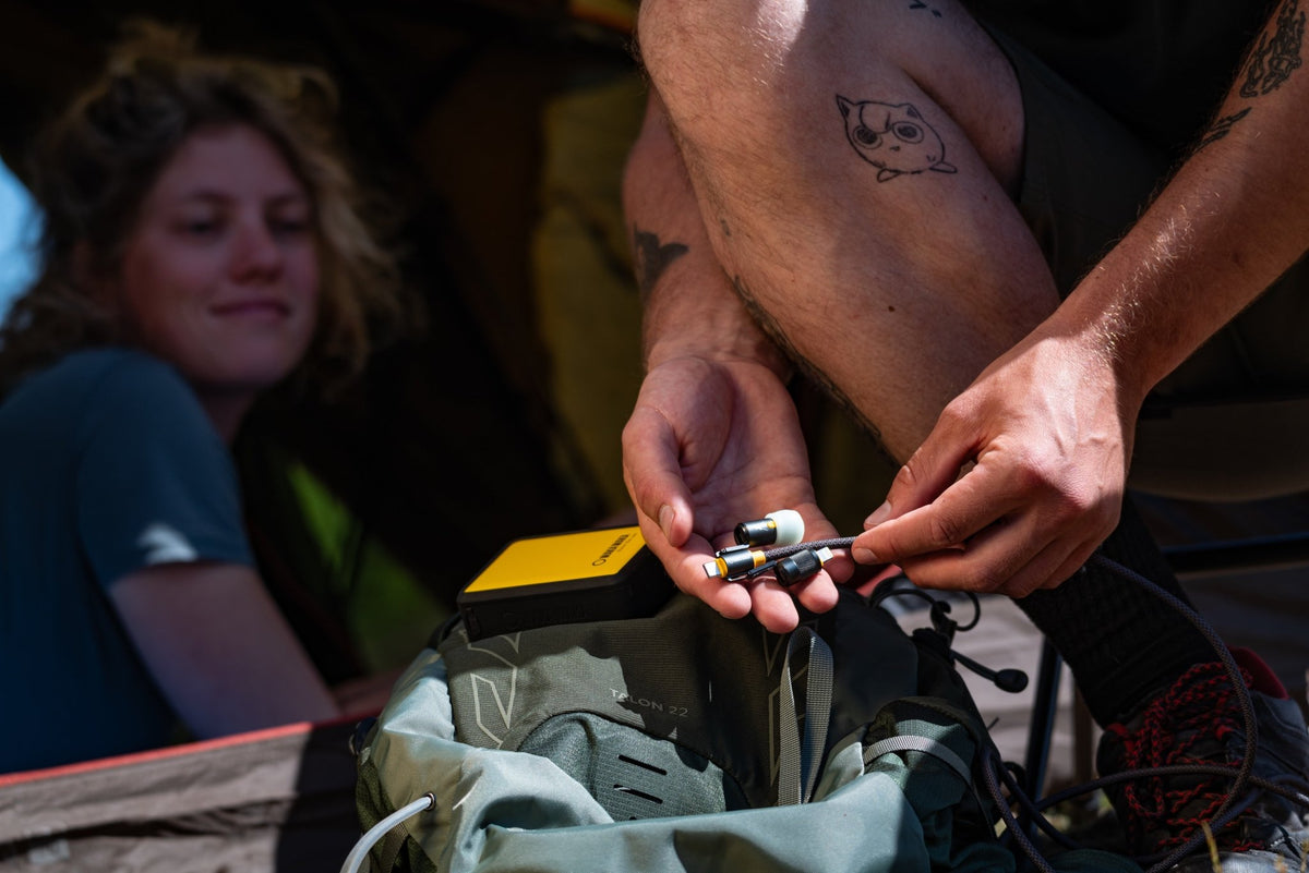 WakaWaka Connect Pro branché dehors sur une batterie externe jaune au-dessus d'un sac à dos