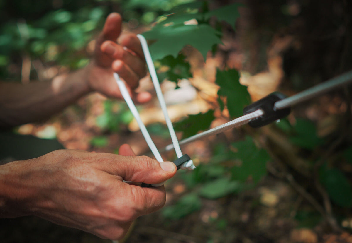 Hauban CanvasCamp avec tendeur tenu à la main dans la forêt