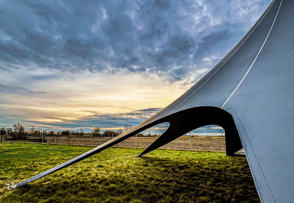Tente événementielle CanvasCamp StarShade Pro au coucher du soleil dans un pré, détail d'un arc