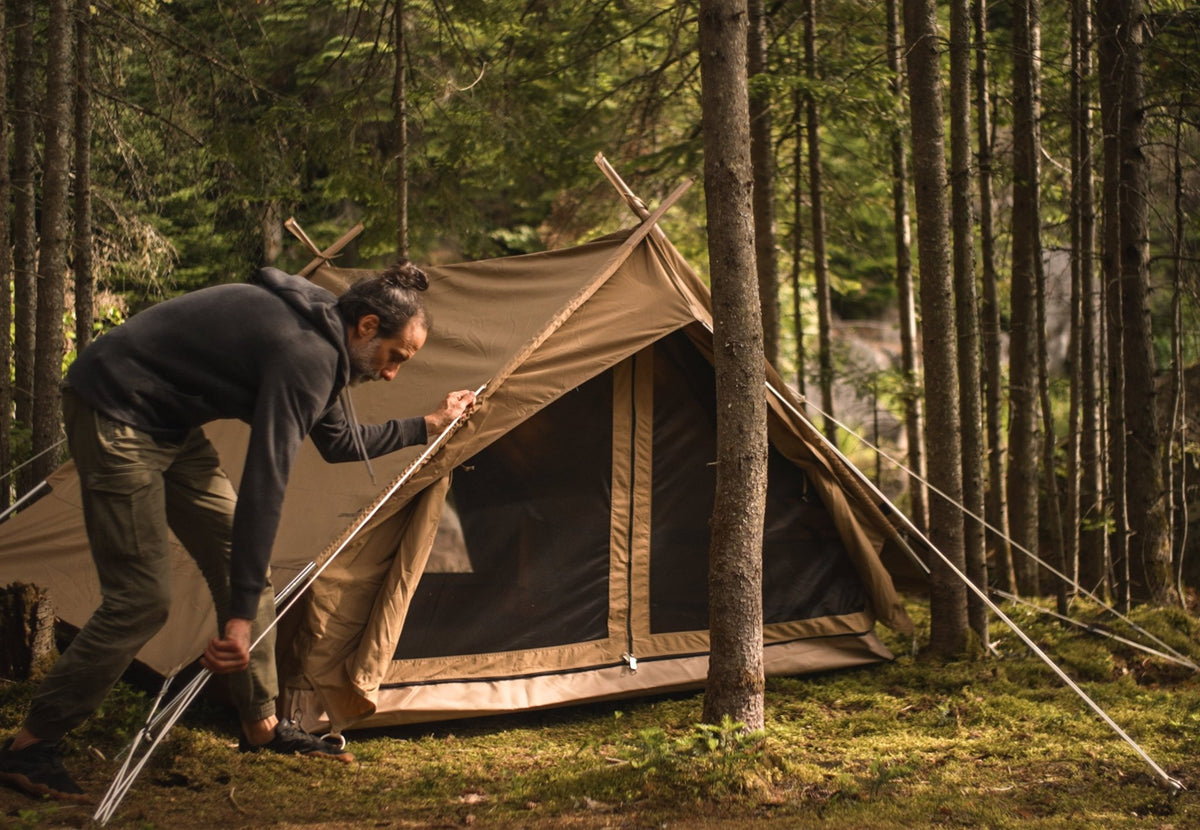 CanvasCamp Altaï montée en forêt par un homme qui tient le mât avant