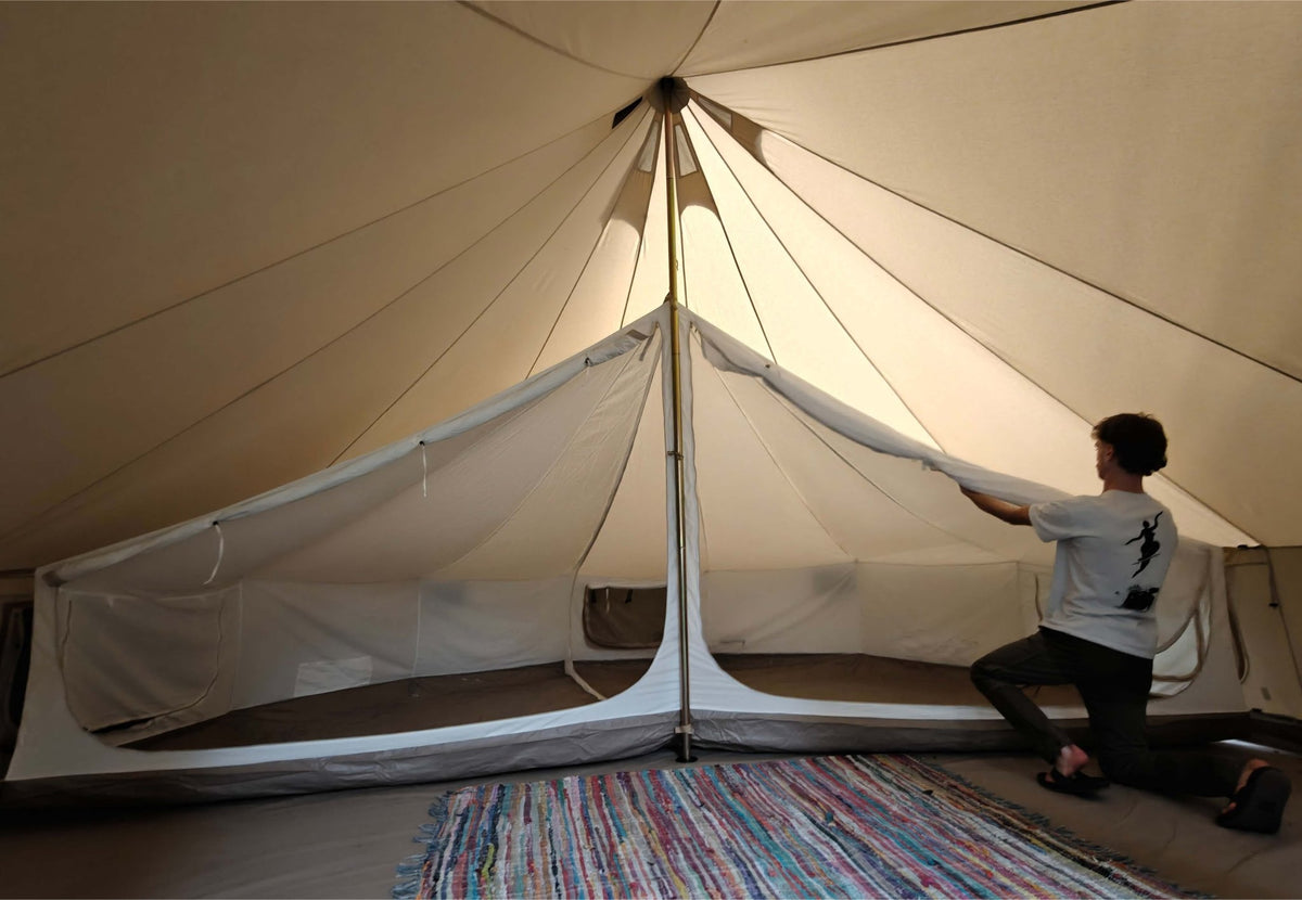 Tente intérieure CanvasCamp Sibley en cours d'installation dans une tente cloche, avec un tapis coloré au sol