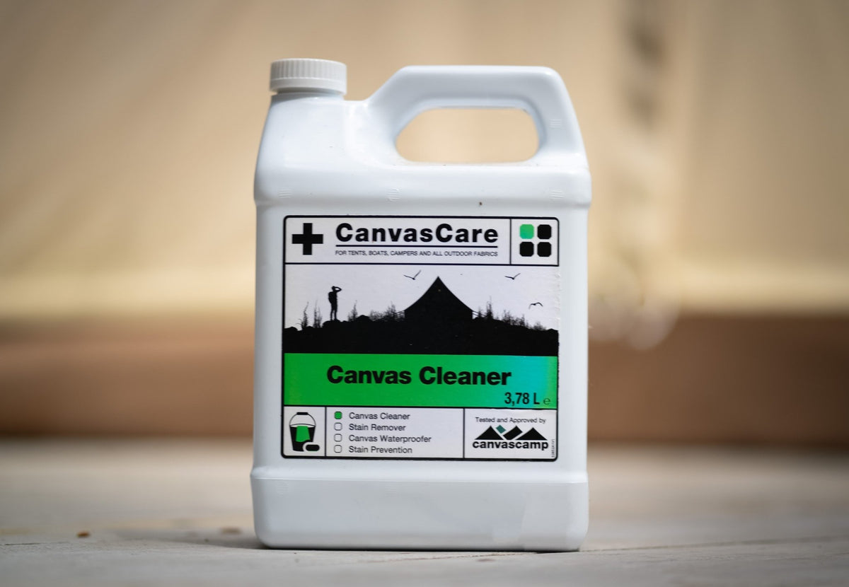 Nettoyant pour toiles CanvasCare, bidon avec poignée sur une plateforme en bois devant une tente