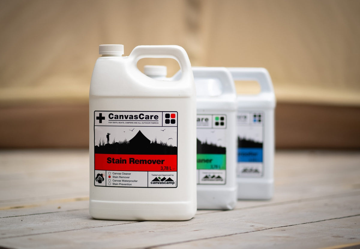 Détachant CanvasCare au premier plan sur un sol en bois, avec deux autres bidons CanvasCare derrière