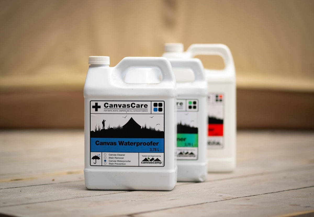 Imperméabilisant CanvasCare au premier plan sur une plateforme en bois, près de bidons à étiquette verte et rouge