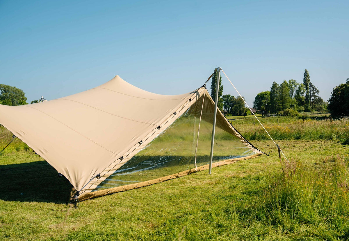 porte pour Stretch Tent montée sur une tente stretch beige avec mât et haubans sur une pelouse