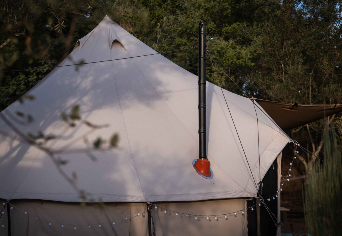 CanvasCamp Exit 45° sur une tente cloche claire avec guirlande lumineuse, tuyau de poêle à travers le toit