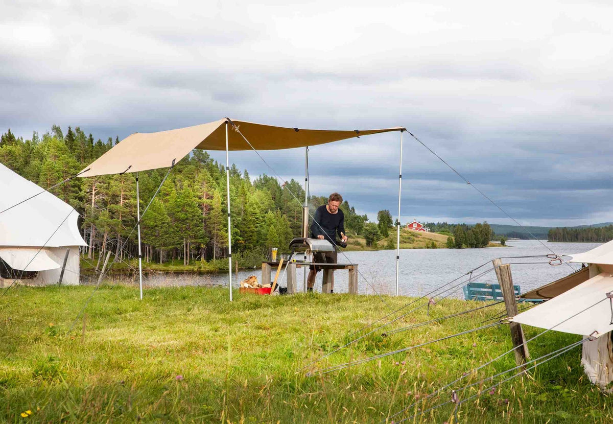 CanvasCamp Heavy Duty Shelter en auvent au bord de l'eau, avec un homme à une table dessous