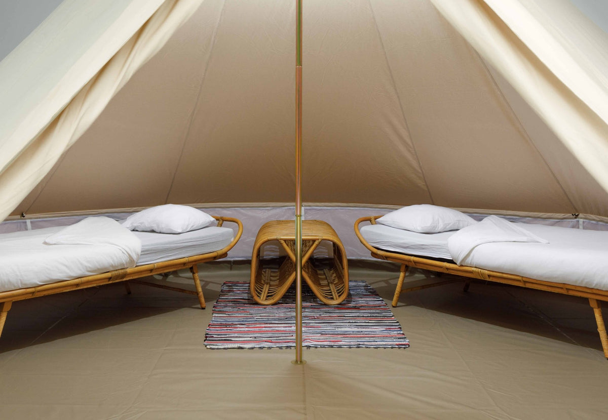 Tapis de tente coloré CanvasCamp entre deux lits avec une petite table d'appoint dans une tente
