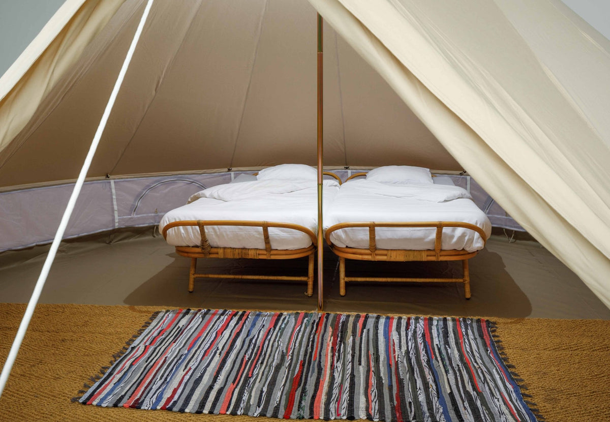 Tapis de tente coloré CanvasCamp au sol devant deux lits dans une tente