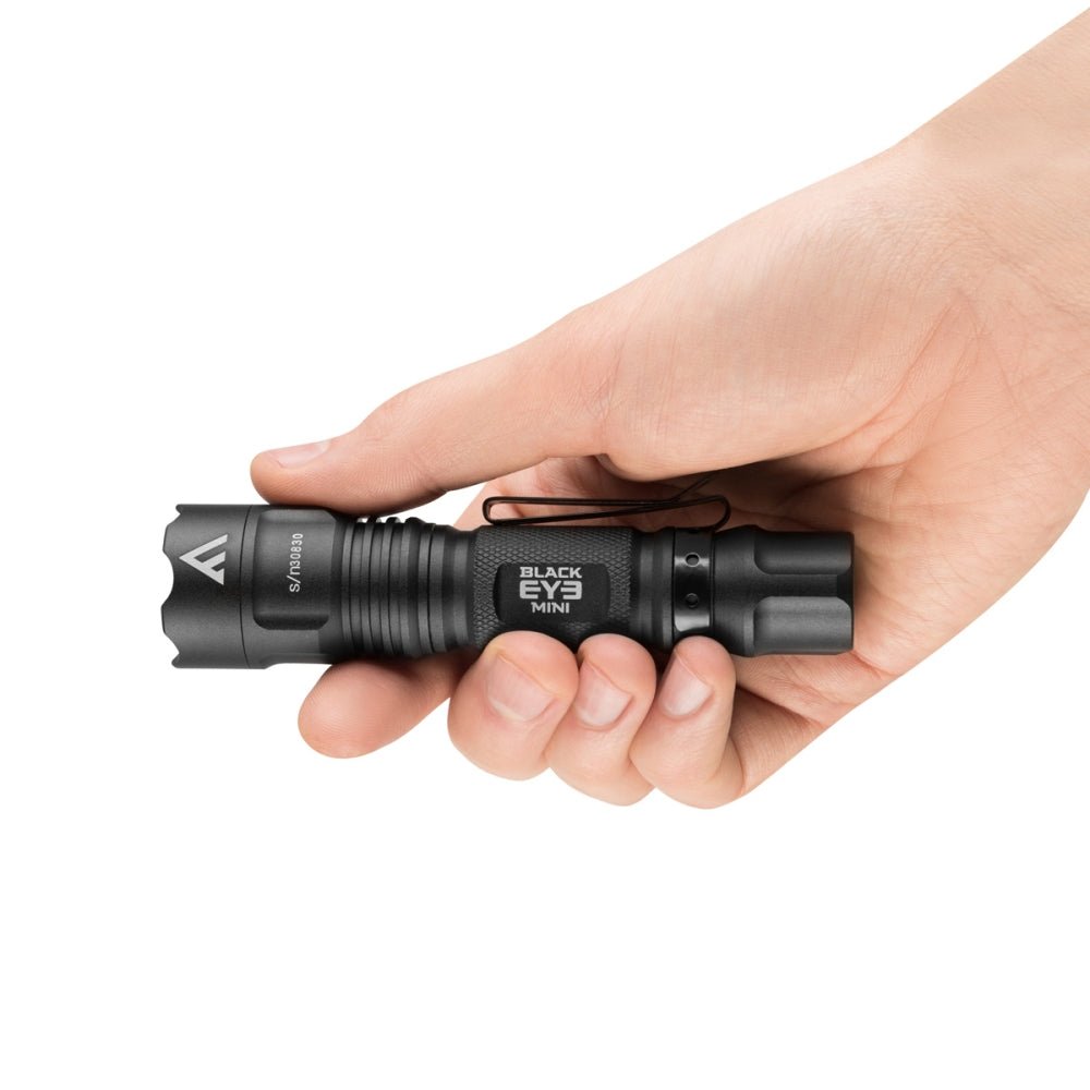 Mactronic Black Eye Mini lampe de poche noire compacte en main, avec inscription sur le boîtier
