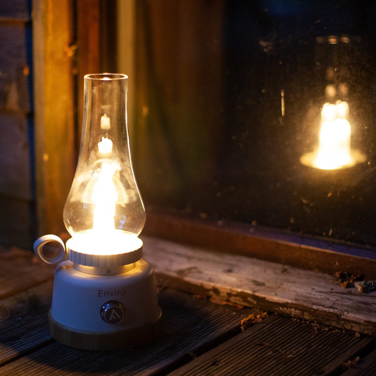Lampe de table Mactronic Enviro allumée dans le noir près d'une fenêtre avec reflet