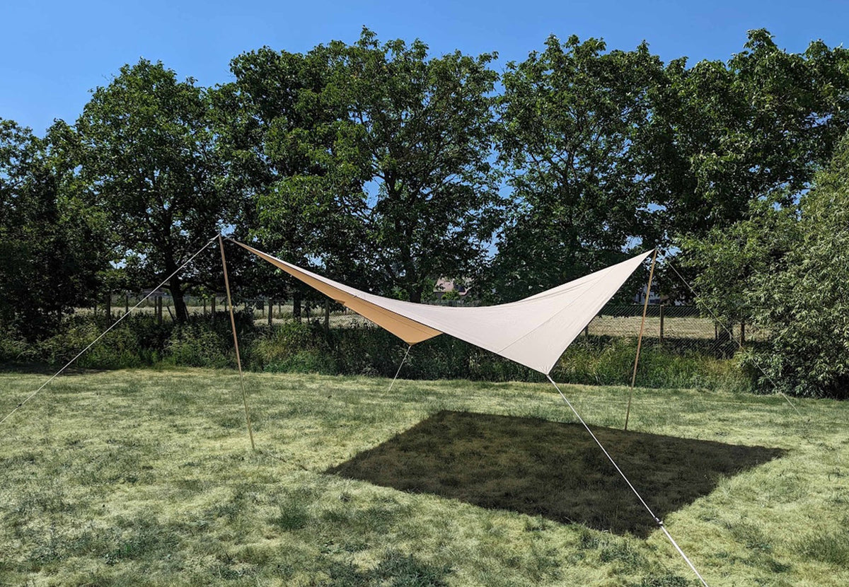 Auvent CanvasCamp Malu tendu sur une pelouse avec des arbres et de l'ombre dessous