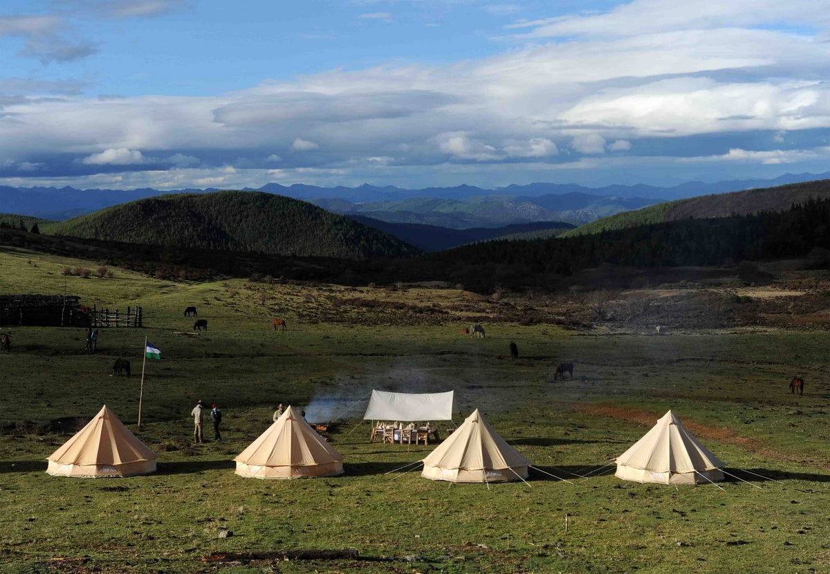 Auvent CanvasCamp Malu au-dessus d'une table entre quatre tentes cloches en montagne