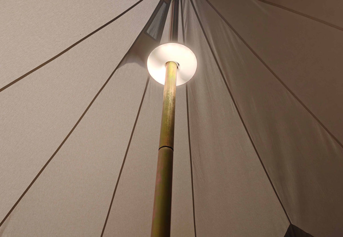 Éclairage de tente rechargeable CanvasCamp allumé autour du mât central d'une tente