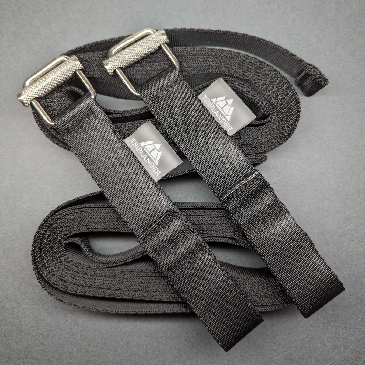 Triplander Quick Drag, deux sangles noires enroulées avec boucles et étiquettes logo