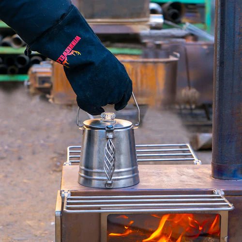 Gant Winnerwell soulevant une bouilloire en métal d'un poêle à bois allumé