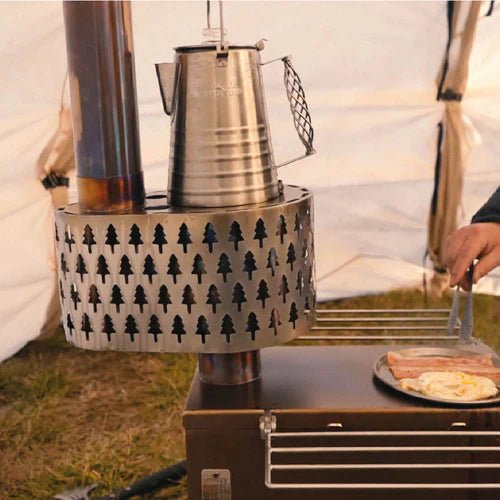 Brûleur secondaire Winnerwell en service dans une tente avec une bouilloire dessus et du lard sur le poêle