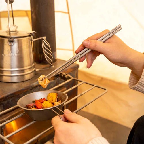 Baguettes en titane Winnerwell utilisées pendant un repas à côté d'un poêle de tente sous la tente