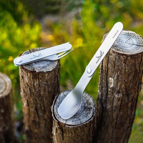 Fourchette et cuillère en titane Winnerwell dehors sur des piquets en bois dans la verdure