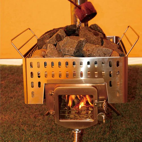 Winnerwell Woodlander Sauna Stove avec pierres de sauna dans le panier et feu derrière la vitre